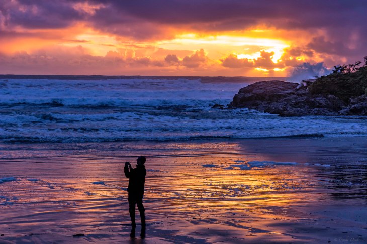 man taking pictures on a beach during sunset